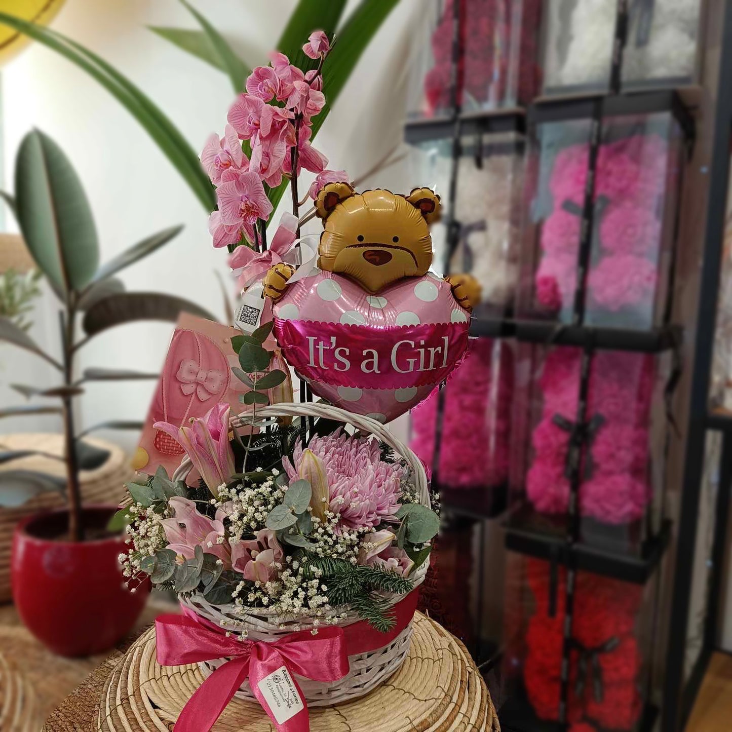 Ψάθινο καλάθι It’s a Girl με σύνθεση λουλουδιών Oriental, Ντάλιες και ορχιδέα
 Ανθοσύνθεση με ροζ ορχιδέα, ευκάλυπτο και έλατο σε ψάθινο καλάθι δώρου : Μπαλόνι αρκουδάκι It’s a Girl με ανθοσύνθεση σε καλάθι: Δώρο για νεογέννητο κορίτσι με Oriental, Ντάλιες και ροζ ορχιδέα: Premium ανθοσύνθεση Blossom Stories σε ψάθινο καλάθι για μαιευτήριο
